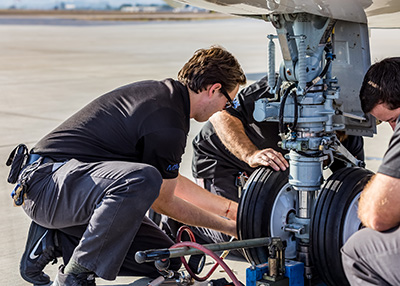 Aircraft Maintenance - Photo of two Mechanics repairing Airplane Tire